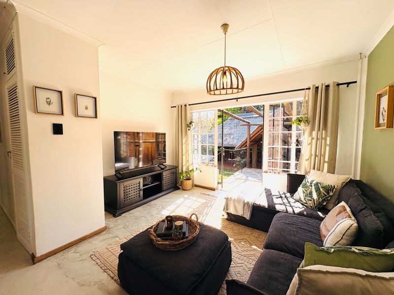 A bright living room featuring polished concrete floors, a pendant light, and french doors opening to an outdoor area.