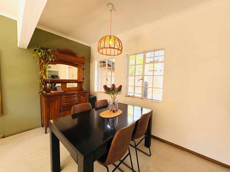A bright dining room featuring steel-framed windows, a coved ceiling, and a central pendant light fixture.