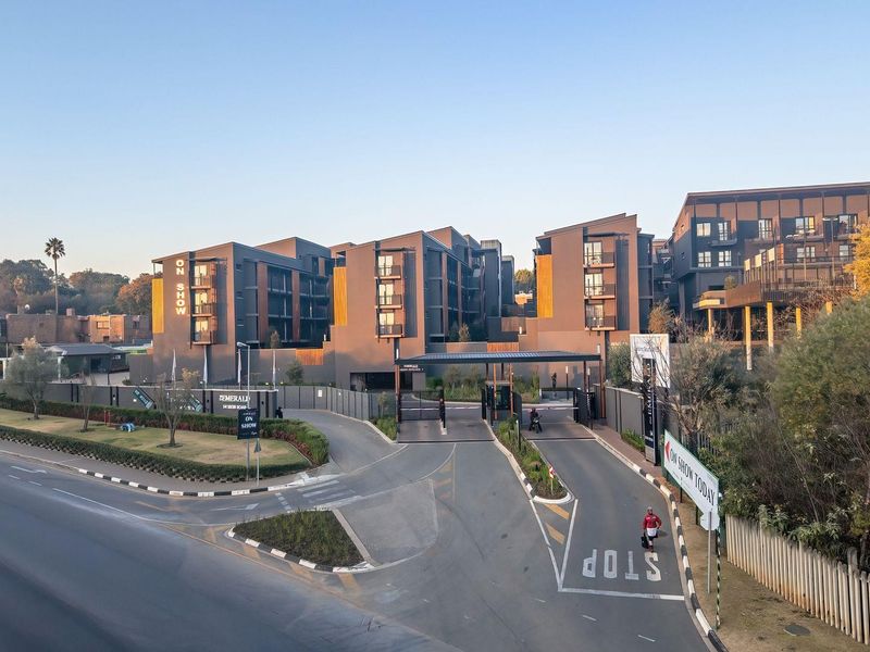Aerial view of the modern apartment complex entrance, featuring secure gated access, paved driveway, and contemporary architectural design.