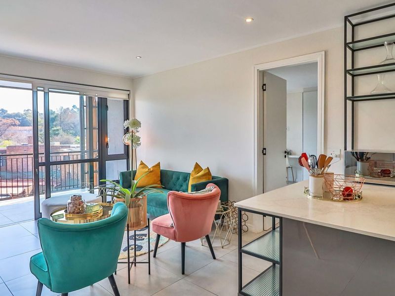 Modern open-plan living area featuring tiled floors, recessed lighting, and a sleek kitchen with stone countertops, flowing onto a private balcony.