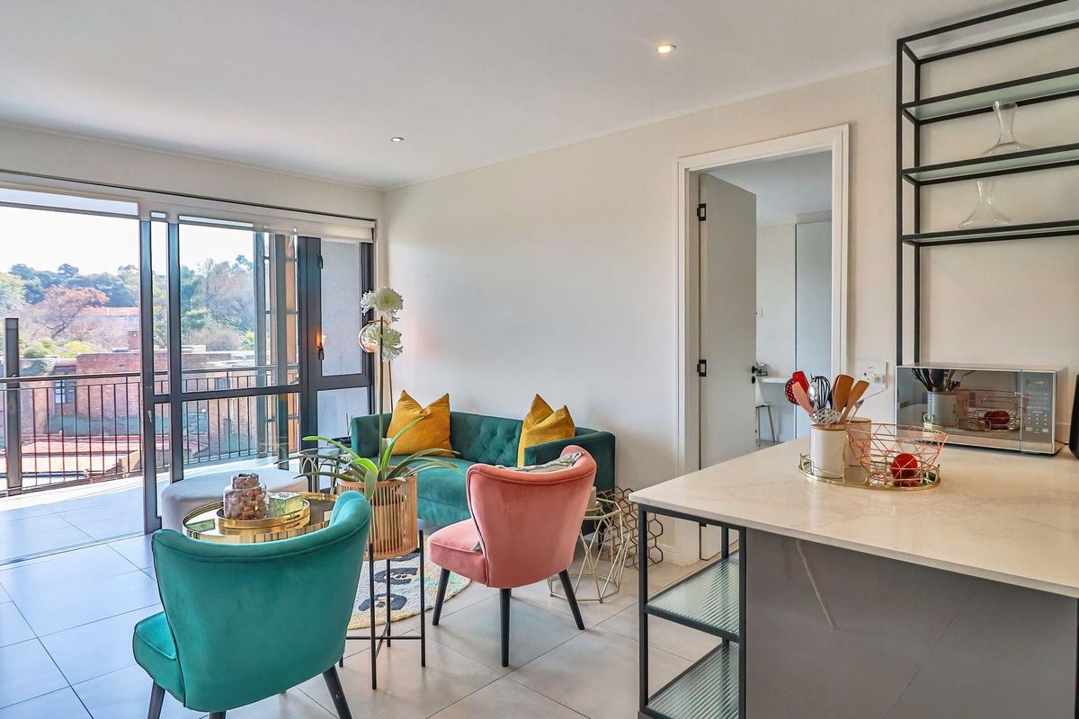 Modern open-plan living area featuring tiled floors, recessed lighting, and a sleek kitchen with stone countertops, flowing onto a private balcony.