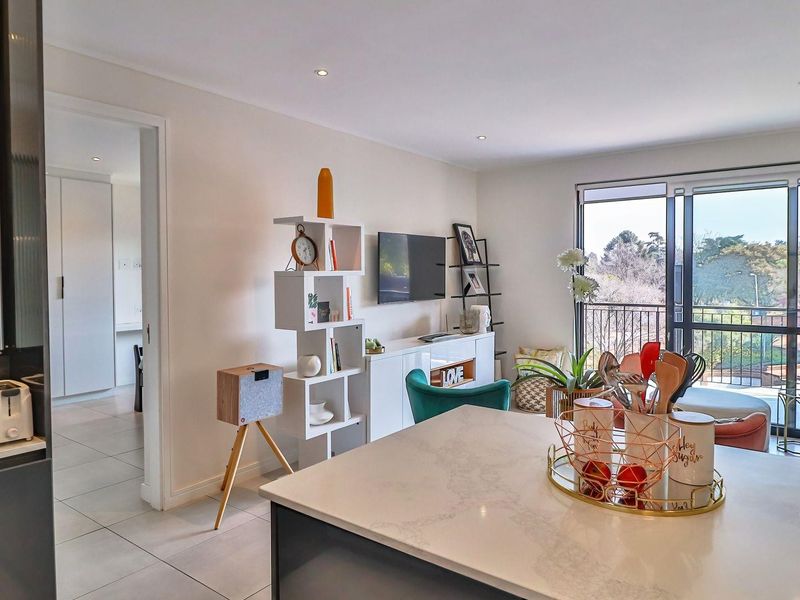 Modern open-plan living area featuring a stone kitchen island, recessed lighting, and large sliding doors leading to a private balcony.