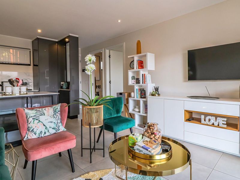 Modern open-plan living area featuring tiled floors, recessed lighting, and a sleek kitchen with stone countertops and integrated cabinetry.