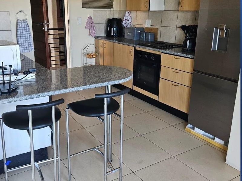 Functional kitchen featuring granite countertops, built-in oven, gas hob, and laminate cabinetry with tiled flooring and backsplash.