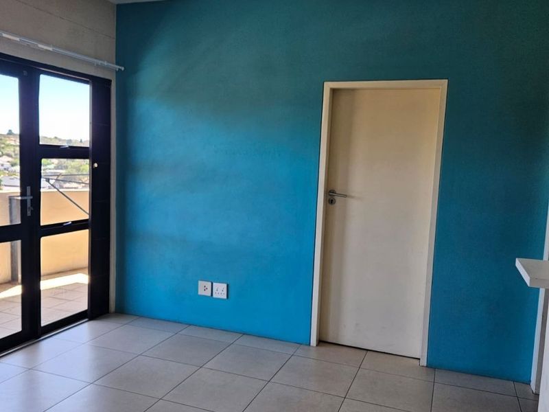An empty living area featuring tiled flooring, a bright blue accent wall, and a double glass door leading to an outdoor space.