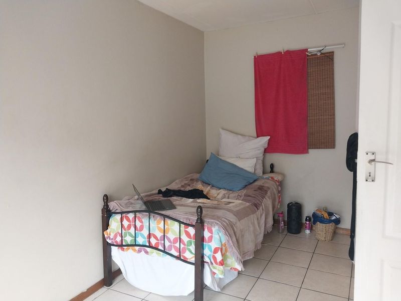 A compact bedroom featuring tiled flooring and neutral wall finishes, providing a functional space ready for personalization and cosmetic updates.