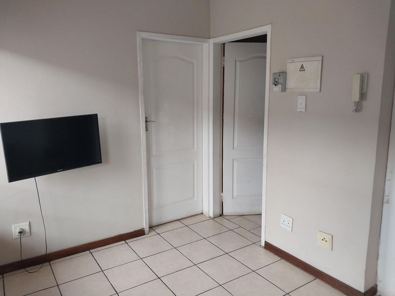 A functional hallway area featuring tiled flooring, an intercom system, and an electrical distribution board, providing access to adjacent rooms.