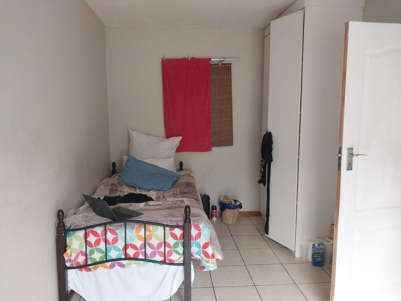 A compact bedroom featuring tiled flooring and a built-in wardrobe, offering a functional space for a single bed.