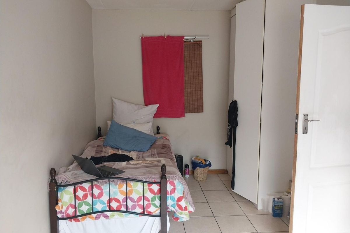 A compact bedroom featuring tiled flooring and a built-in wardrobe, offering a functional space for a single bed.