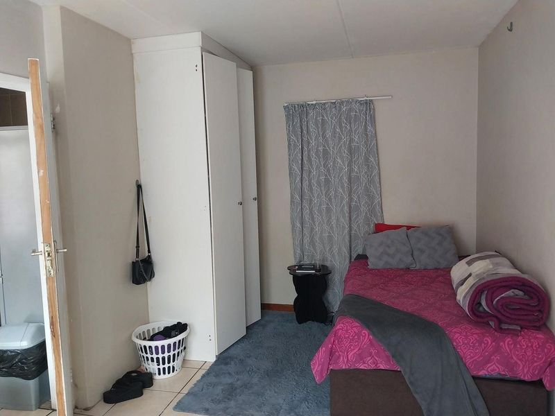 A functional bedroom featuring tiled flooring and a built-in wardrobe, providing essential storage space.