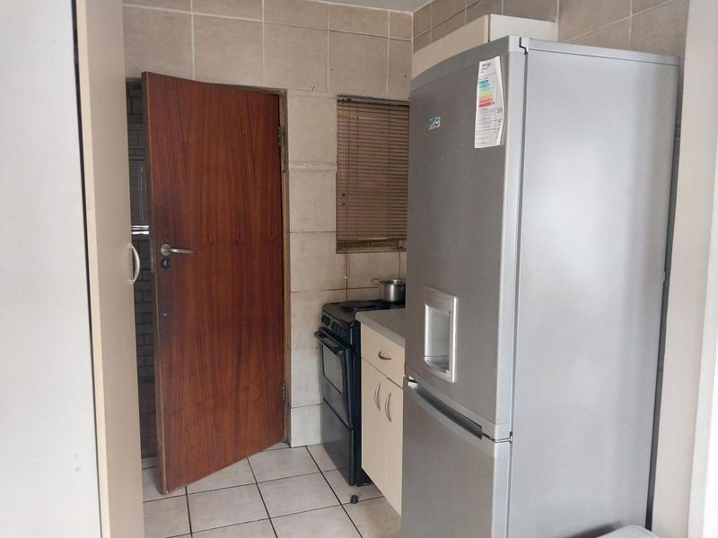 A compact kitchen area featuring tiled flooring, wall splashbacks, and built-in cabinetry, providing a functional space that could benefit from modern updates.