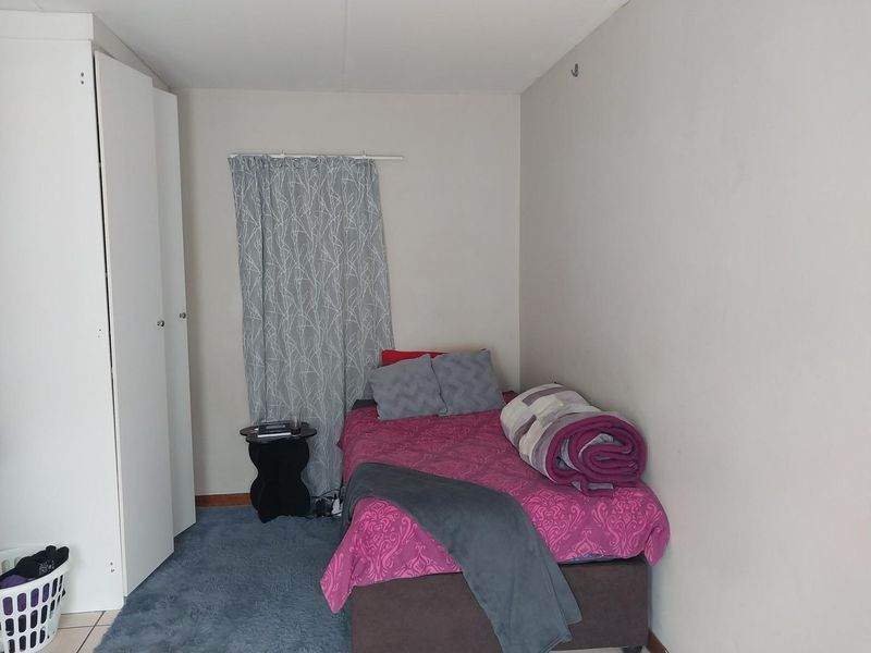 A compact bedroom featuring a built-in wardrobe and neutral wall finishes, providing a functional space for rest.
