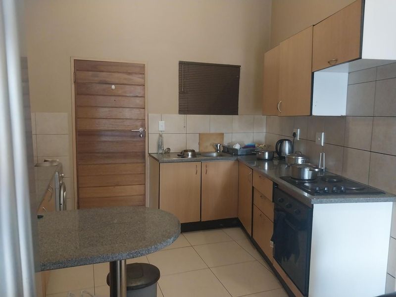 Functional kitchen featuring light wood cabinetry, granite countertops, built-in oven, gas hob, and a convenient breakfast nook with tiled flooring.