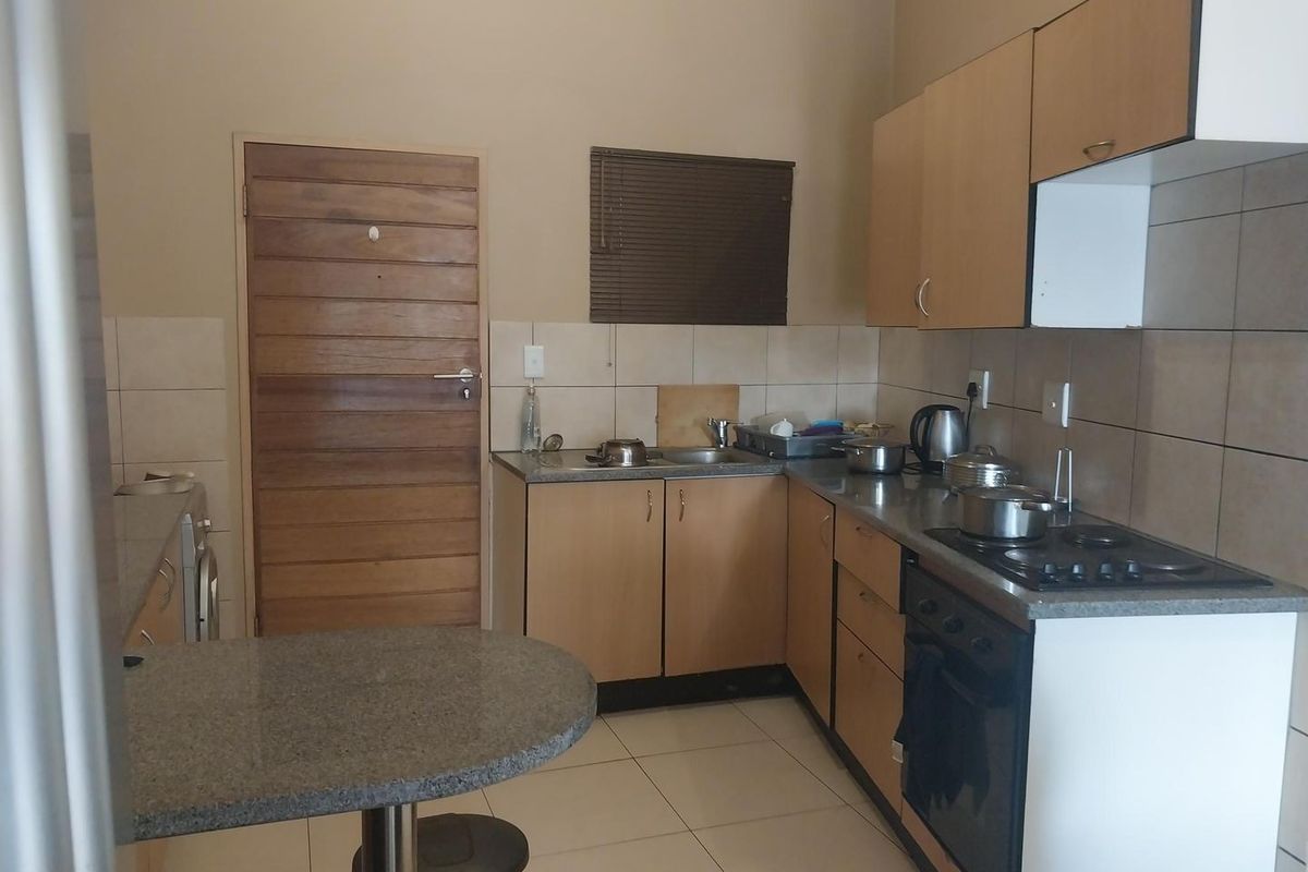 Functional kitchen featuring light wood cabinetry, granite countertops, built-in oven, gas hob, and a convenient breakfast nook with tiled flooring.