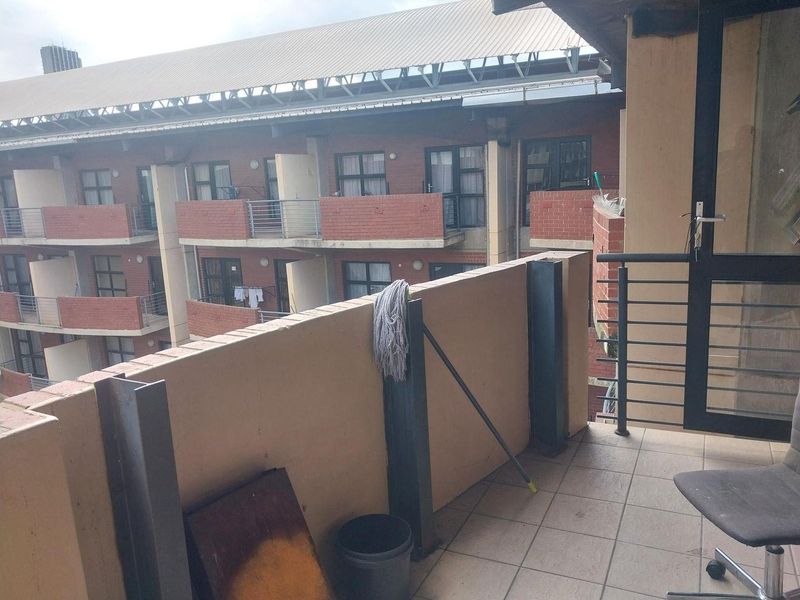 A functional balcony area with tiled flooring and metal railings, overlooking the adjacent apartment building complex.