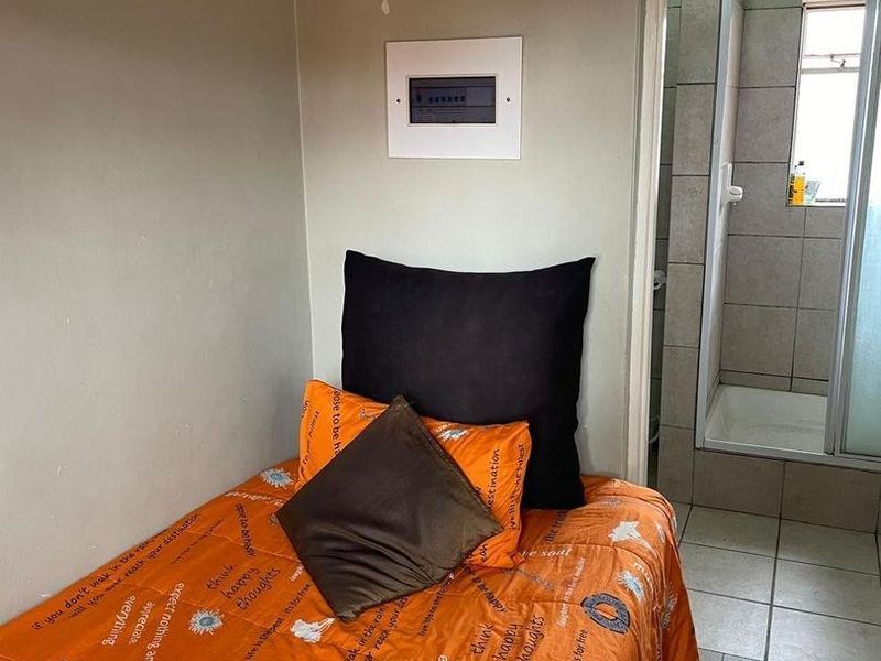Bedroom featuring tiled flooring and an integrated electrical distribution board, with direct access to an en-suite bathroom containing a shower enclosure.