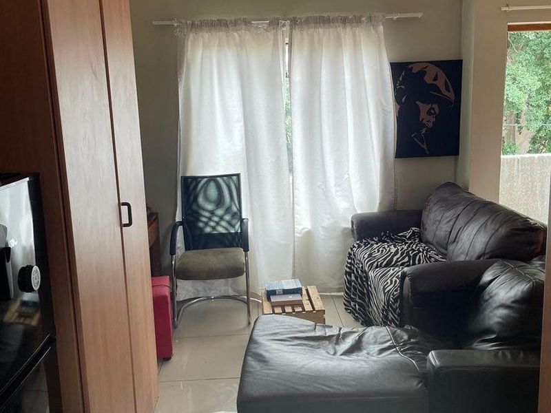 A compact living area featuring tiled flooring and a built-in cupboard, providing functional storage space within the apartment layout.
