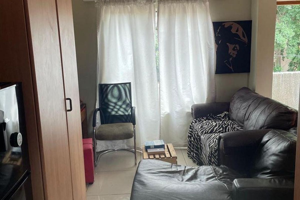 A compact living area featuring tiled flooring and a built-in cupboard, providing functional storage space within the apartment layout.