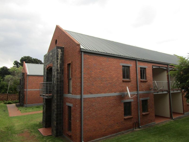 Exterior view of a multi-story apartment complex featuring face brick construction, metal roofing, and private balconies with steel railings.
