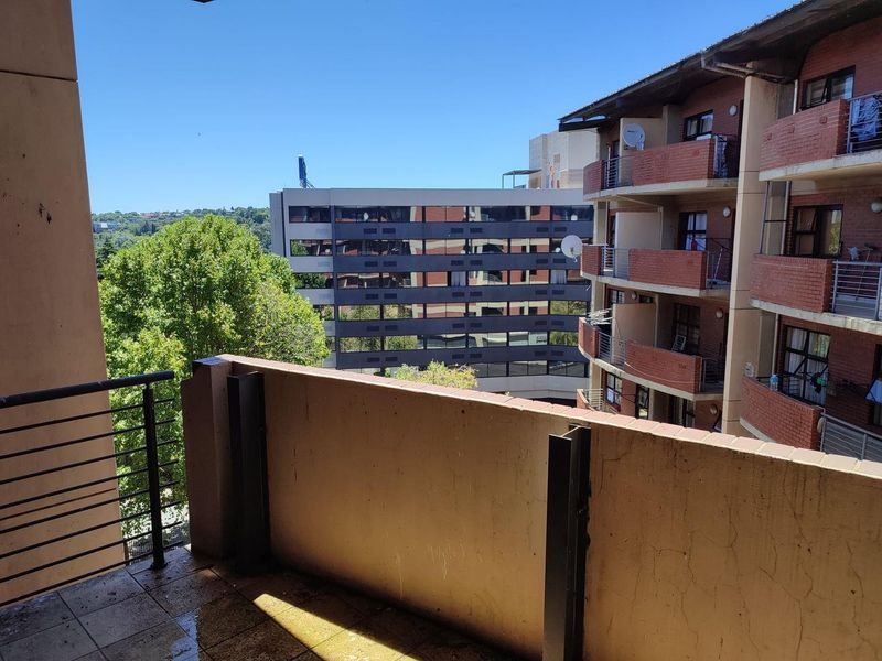 A balcony area featuring tiled flooring and a brick parapet wall, offering an elevated view of the surrounding apartment complex.