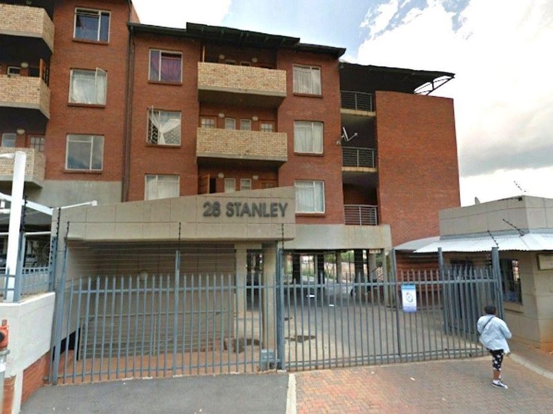 Front exterior view of 28 Stanley apartment complex, featuring a brick facade, balconies, and secure gated entrance with a guard house.