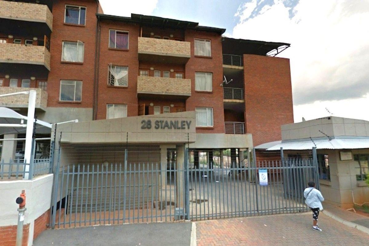 Front exterior view of 28 Stanley apartment complex, featuring a brick facade, balconies, and secure gated entrance with a guard house.