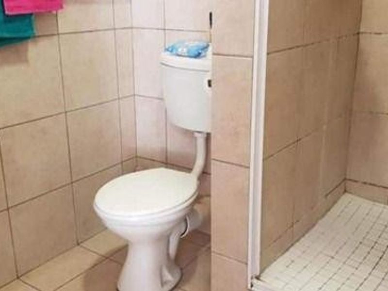 A compact bathroom featuring a pedestal basin, standard toilet, and a shower enclosure with tiled walls.