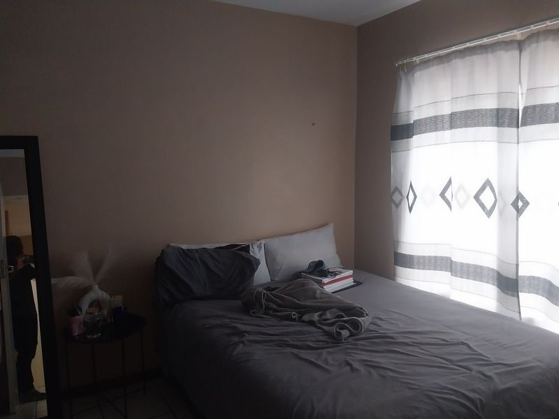 A standard bedroom featuring tiled flooring and a window with a curtain rail, providing a functional space for rest.