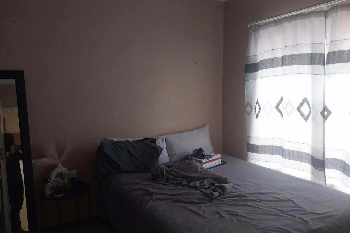 A standard bedroom featuring tiled flooring and a window with a curtain rail, providing a functional space for rest.