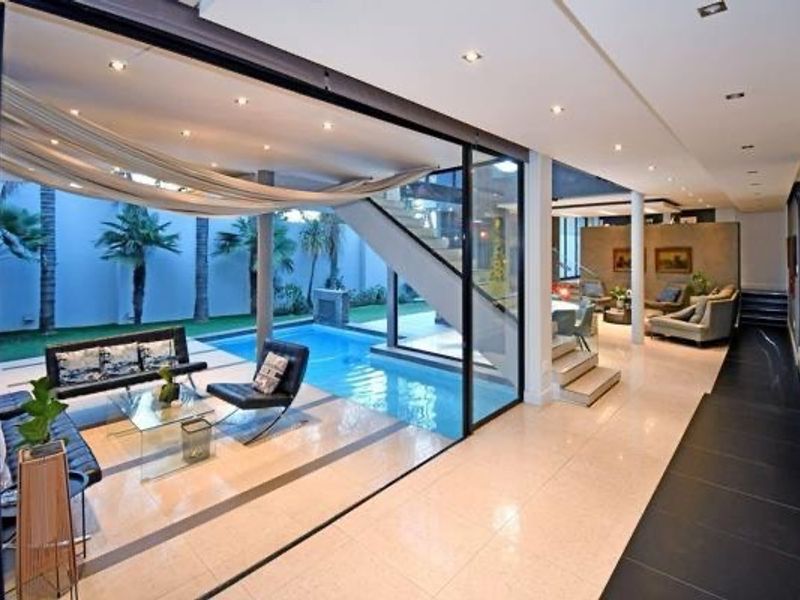 Modern open-plan living area featuring seamless indoor-outdoor flow to a private swimming pool, complemented by high-end finishes and architectural staircase.