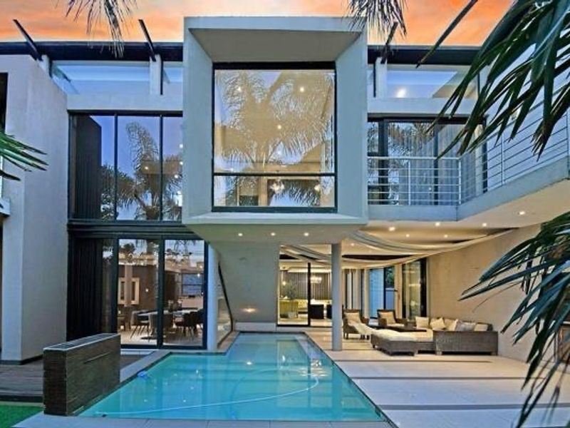 Modern rear exterior featuring a swimming pool, expansive glass sliding doors, a covered patio area, and a contemporary multi-level architectural design.