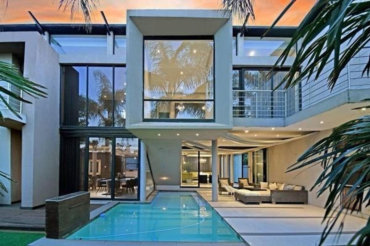 Modern rear exterior featuring a swimming pool, expansive glass sliding doors, a covered patio area, and a contemporary multi-level architectural design.