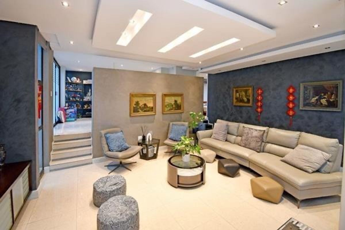 A well-maintained living room featuring a modern dropped ceiling with recessed lighting, tiled floors, and a stylish textured feature wall.