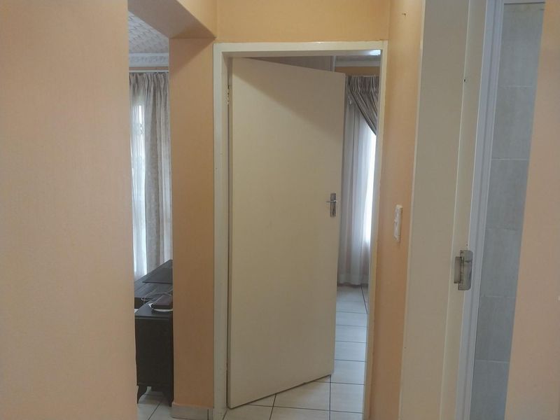 A view through a hallway connecting interior rooms, featuring tiled flooring and standard internal doors.