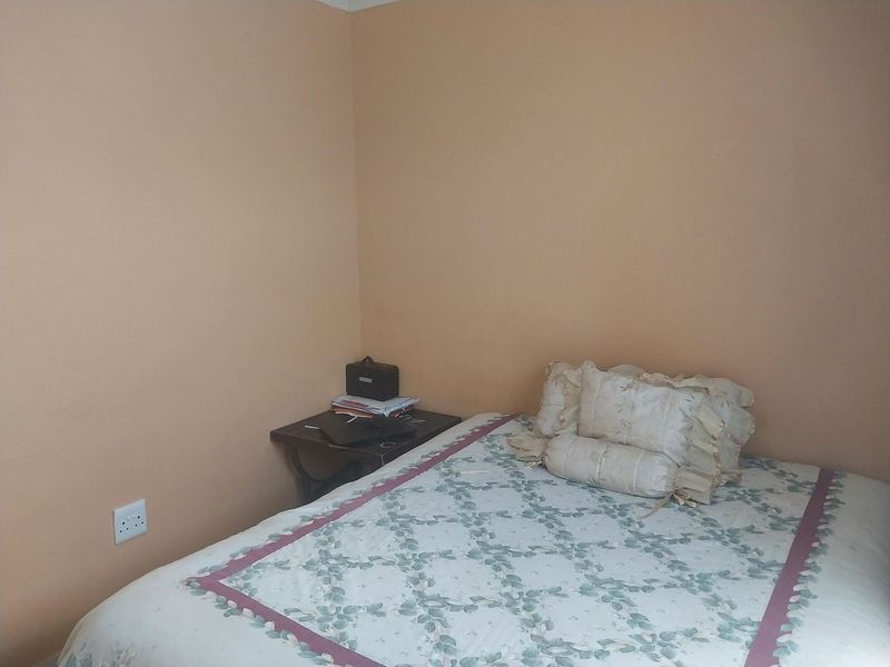 A simple bedroom featuring plain painted walls and a standard electrical power outlet.