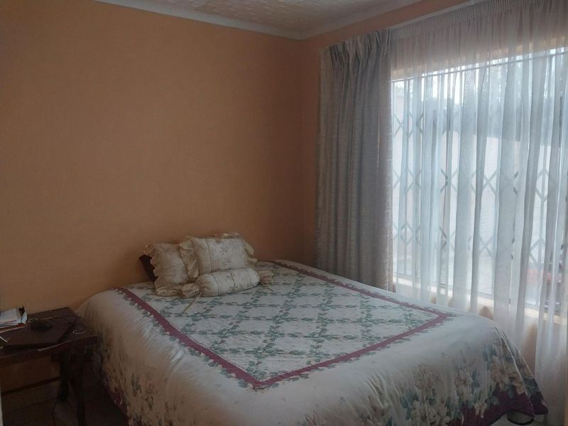 A bedroom featuring a large window with a fitted security gate and curtain tracks, providing natural light.