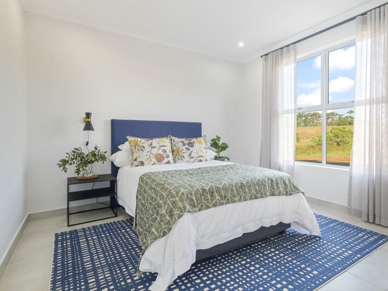 A bright and modern bedroom featuring neutral walls, tiled flooring, and a large window providing natural light and scenic views.