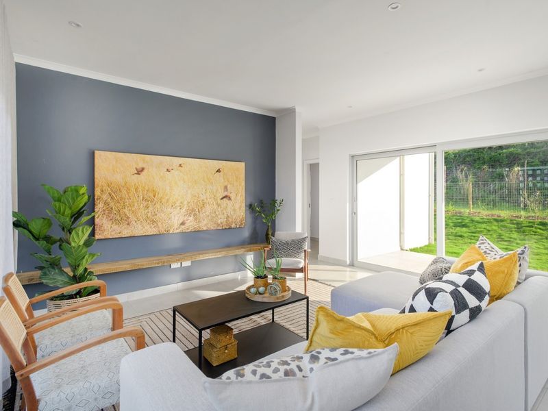 Bright and modern living room featuring a feature wall, recessed downlights, and large sliding glass doors providing seamless access to the outdoor garden area.