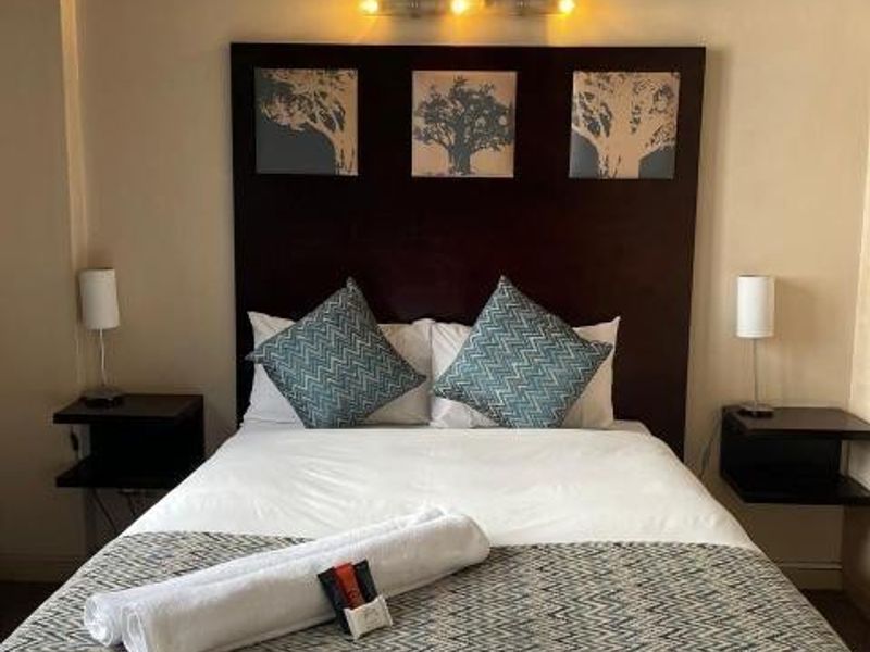 A bedroom featuring a dark wood built-in headboard and a wall-mounted light fixture above the bed.