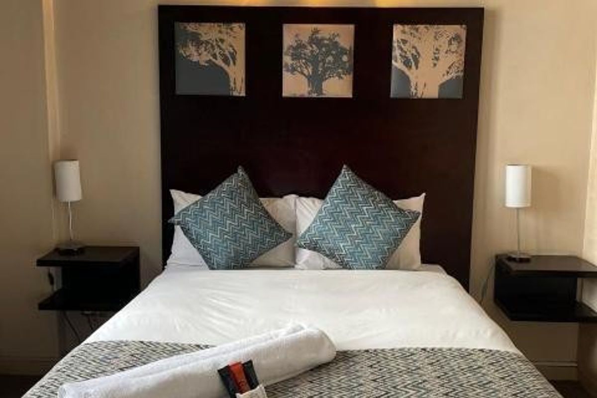 A bedroom featuring a dark wood built-in headboard and a wall-mounted light fixture above the bed.