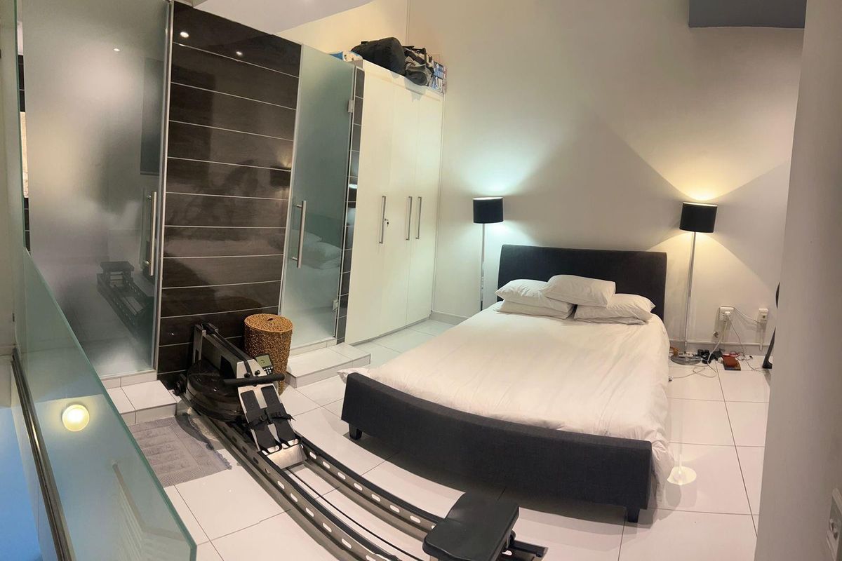 A modern bedroom featuring tiled flooring, a built-in wardrobe, and a glass-enclosed en-suite bathroom area.
