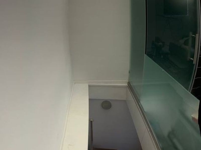A vertical view of a staircase featuring timber treads and a modern glass balustrade, illuminated by overhead skylights.
