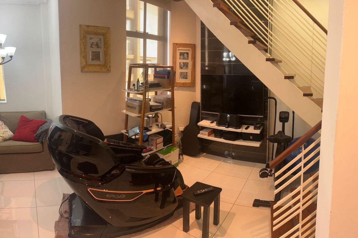 A living area featuring tiled flooring, a staircase with a metal balustrade, and a built-in media wall unit.