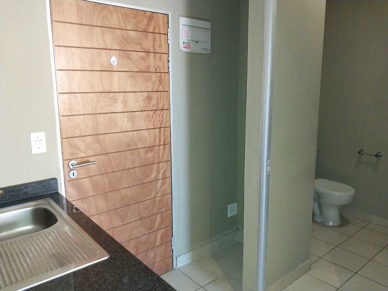 A functional kitchen area featuring a stainless steel sink, granite countertops, and an adjacent bathroom with tiled flooring.