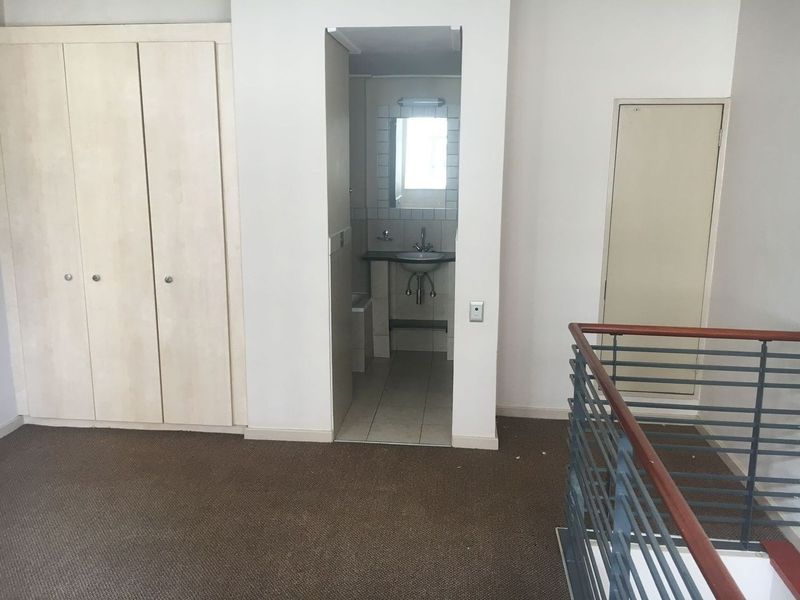 Spacious bedroom featuring built-in cupboards, carpeted flooring, and an open-plan en-suite bathroom with a pedestal basin.