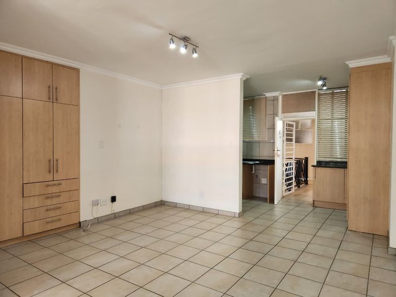 Spacious open-plan living area featuring neutral tiled flooring, ample built-in storage, and a functional kitchen with granite countertops and modern cabinetry.