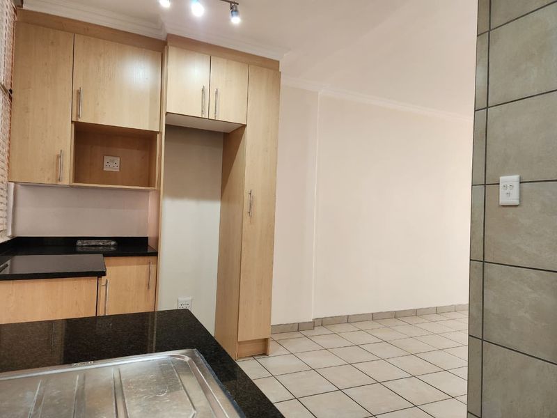 A clean, functional kitchen featuring light wood-finish cabinetry, dark granite countertops, and neutral floor tiles, offering a bright and well-maintained space.