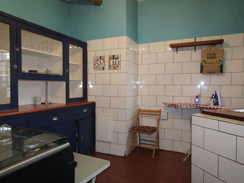 A kitchen area featuring dark blue built-in cabinetry, white subway tile backsplash, and a gas hob, offering a functional layout with potential for modernization.