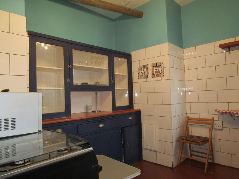 A kitchen area featuring dark blue built-in cabinetry with glass-fronted display sections and white subway tile wall finishes.