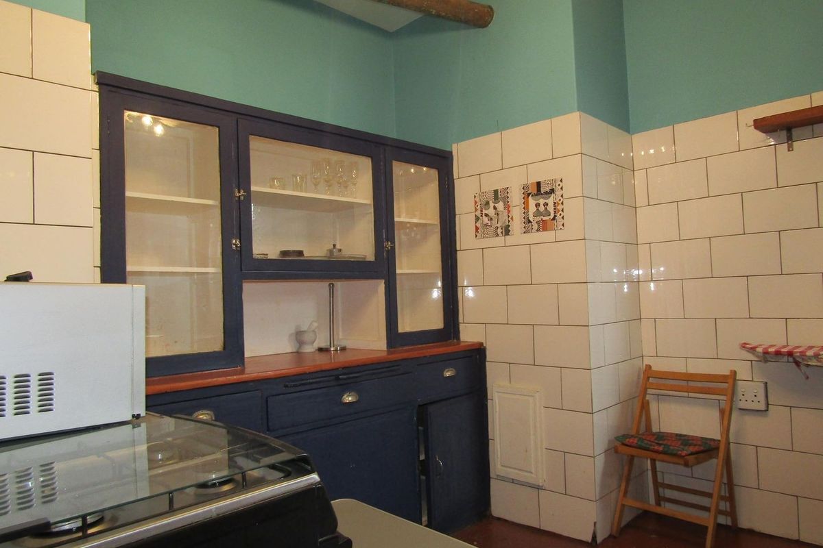 A kitchen area featuring dark blue built-in cabinetry with glass-fronted display sections and white subway tile wall finishes.
